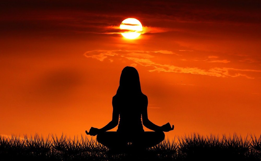 Frau macht Yoga bei Sonnenuntergang