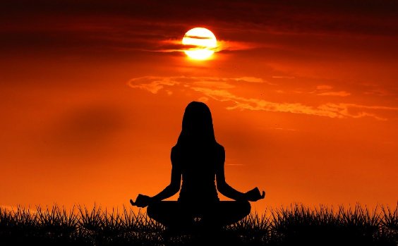 Frau macht Yoga bei Sonnenuntergang
